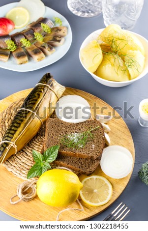 Sliced salted fish with lemon and seasoning, boiled potatoes on a table