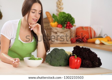 Young woman cooking in kitchen. Householding, tasty food and digital technology in lifestyle concepts