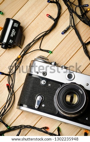 Old vintage film camera, film and lights garland on wooden boards, top view, vertically