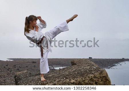 Young Woman in Kimono practicing karate, Japanese martial arts on river coast. Early foggy morning Royalty-Free Stock Photo #1302258346