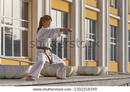 Young Woman in Kimono doing formal karate exercising on cityscape background