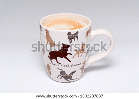 Cup of coffee with man's best friend and pictures of dogs printed on side of coffee mug on isolated white background.