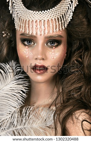 close up portrait of beautiful girl. professional makeup. queen with beautiful diadem. feathers on face