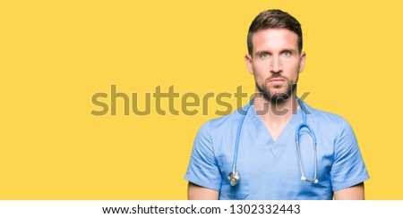 Handsome doctor man wearing medical uniform over isolated background Relaxed with serious expression on face. Simple and natural looking at the camera.