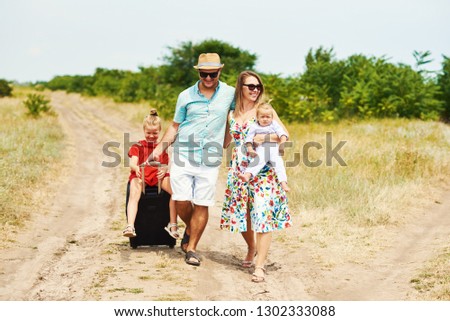 Family, summer vacation, adoption and people concept - happy man, woman and daughters in sunglasses, with suitcases  having fun over blue sky background 