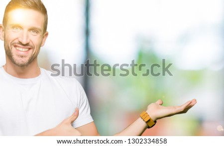 Handsome man wearing casual white t-shirt Showing palm hand and doing ok gesture with thumbs up, smiling happy and cheerful