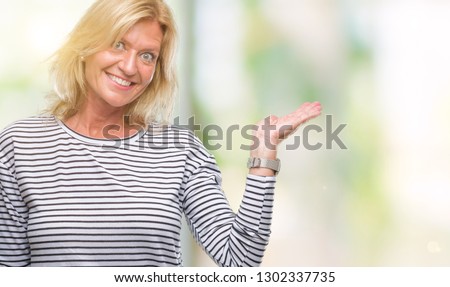Middle age blonde woman over isolated background smiling cheerful presenting and pointing with palm of hand looking at the camera.