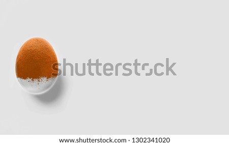 Happy Easter. Orange white spray painted Easter egg on gray background. Colorful holiday design inspiration. Top view. Concept artwork. 