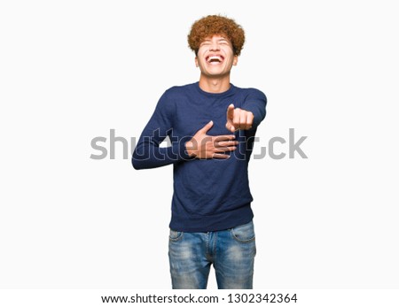 Young handsome man with afro hair Laughing of you, pointing to the camera with finger hand over chest, shame expression