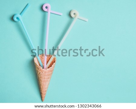 Pastel colors cocktail tubes in a waffle horn on a blue background, top view, flat lay, minimalist trend