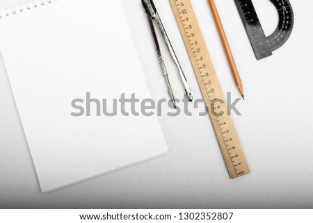 Stationery on a white background. Notebook, compass, protractor, ruler, pencil.