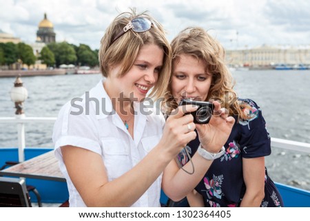 Happy and smiling young European women looking on camera screen at pictures