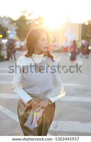 fashion asian girl in Thai traditional costume standing in Bangkok winter festival with sun light effect