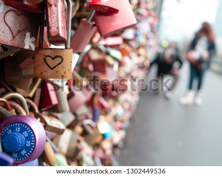 Love locks, placed by couples as symbol for their loce, at Hohenzollern bridge in Cologne, Germany, with couple defocused in background