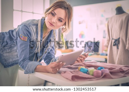 Fashion designer woman working with ipad on her designs in the studio