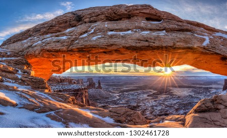 The winter sun rises on a cold January morning at Mesa Arch in Canyonlands National Park, Utah. (panorama) Royalty-Free Stock Photo #1302461728