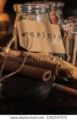 Various exotic spices in glass jars with SPICES text on paper tag.