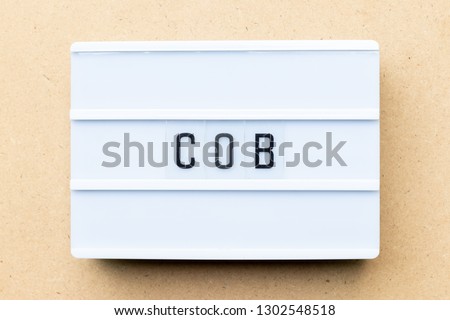 Lightbox with word COB (abbreviation of close of business) on wood background
