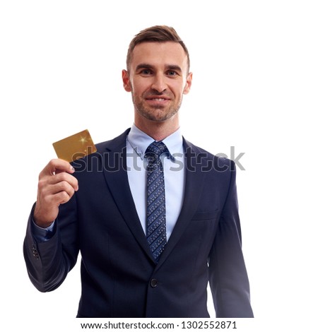 Confident young business man standing isolated over white background, showing credit card.