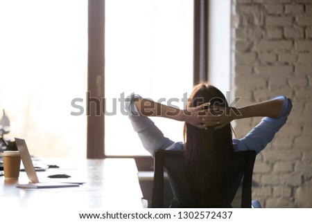 Female freelancer or employee lean back in chair relaxing or taking break from work, calm woman stretch hands over head look in window, dreaming or visualizing, worker have break resting Royalty-Free Stock Photo #1302572437