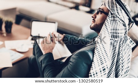 Laptop on table. Arab Businessman. Man Wearing in Black Suit. Experienced Entrepreneur. Successful Young Man. Work in Office. Arab in glasses. Man write at notebook. looking away. close up