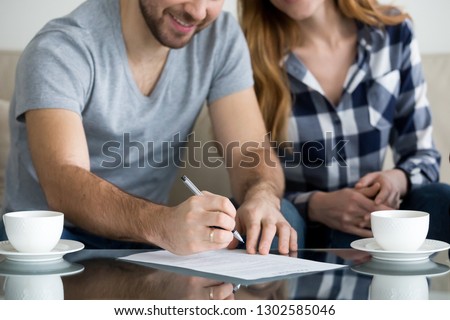 Close up view of couple signing documents, customers renters tenants or clients write signature on rental sale prenuptial agreement or rental contract paper buying real estate or services concept Royalty-Free Stock Photo #1302585046