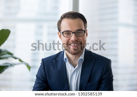 Businessman in suit looking at camera making conference video call, e-coaching training online, recording blog webinar, communicating with client or having distant job interview, headshot portrait Royalty-Free Stock Photo #1302585139