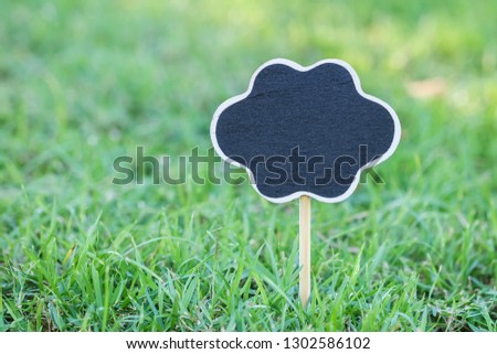 Closeup wooden black board on green grass in the park textured background
