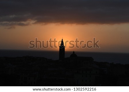 Sunset of the Alghero Cathedral  bell tower (Santa Maria) and of the historic centre. Sardinia, Italy. 
