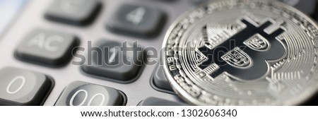 Coin crypto currency bitcoin lies on calculator keyboard background theme silver exchange pyramid for money due to rise or fall exchange rate closeup