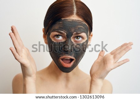 surprised woman in clay mask on a light background portrait