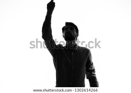 Dark silhouette of a man with a raised hand on a light background             