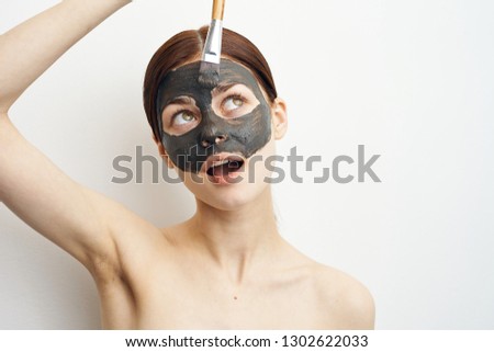 young woman apply clay mask on face with brush care