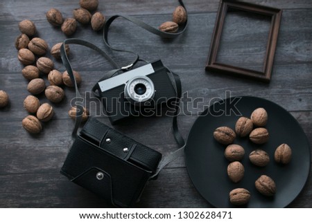 
A vintage camera, a cover from a photo camera, walnuts are located on wooden boards. Still life of items on a rustic background in retro style.