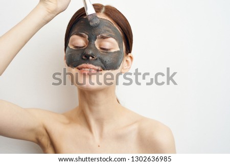 woman puts a cosmetic mask on clay with a brush