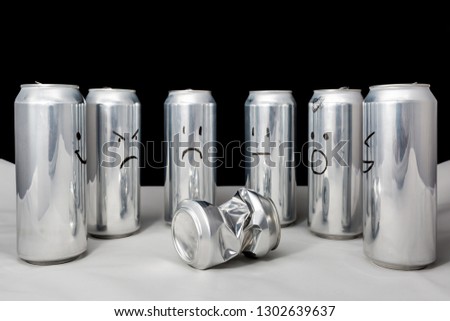 One little beaten surrounded by big. Concept of empty people with different emotions. Aluminium cans with drawned emoji on black background