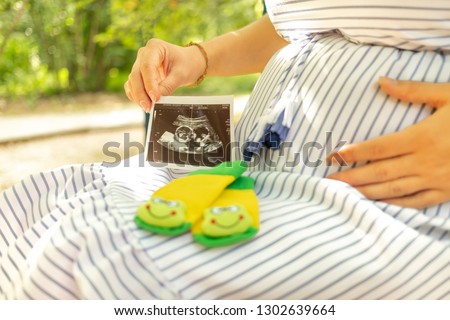 Pregnant woman holding ultrasound sonogram image. Young mother waiting of the baby