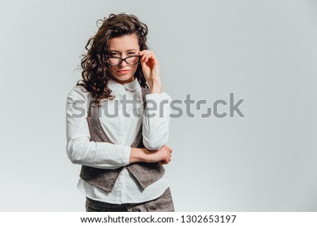 Close-up of a smiling brunette business woman in glasses looking at camera over white background
