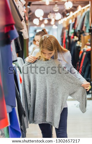 Girl with a girlfriend in a clothing store found a gray sweater that she liked.