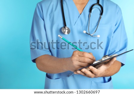 Male doctor with stethoscope and clipboard on color background, closeup. Medical objects