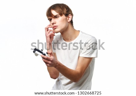 Guy Gamer with a controller from the console in the hands in a white T-shirt on a light background