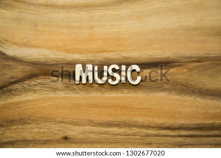 Plywood alphabets on acacia wooden texture background concept. The word "MUSIC" on wood pattern backdrop.
