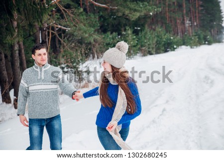 Happy loving couple walking in snowy winter forest