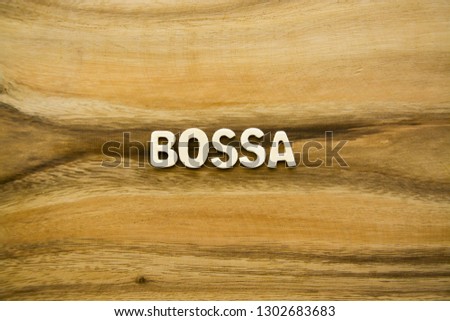 Plywood alphabets on acacia wooden texture background concept. The word "BOSSA" on wood pattern backdrop.