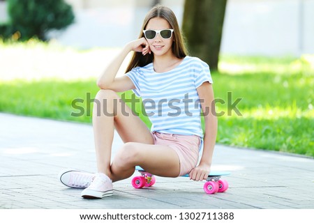 Young girl sitting on skateboard in the park