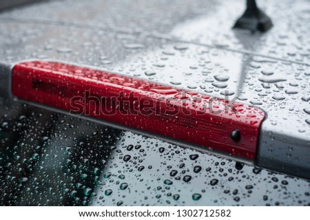 closeup of raindrops on rear lights of on black car