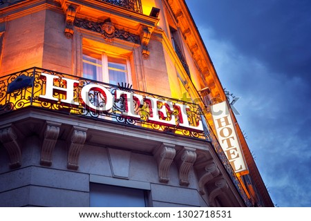 Illuminated hotel sign in Paris at night concept for vacation accomodation and business travel Royalty-Free Stock Photo #1302718531