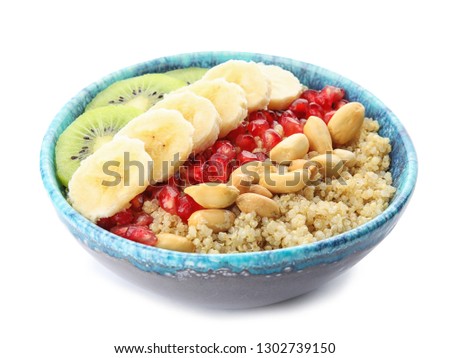 Bowl of quinoa porridge with peanuts, kiwi, banana and pomegranate seeds on white background