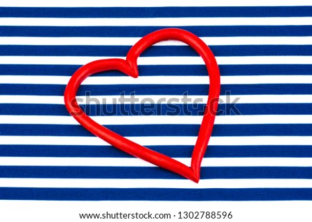 Happy Valentine's Day. Bright striped background in blue and white stripes. Festive atmosphere on Valentine's Day. Heart symbol, plastic heart frame, in the center of the photo