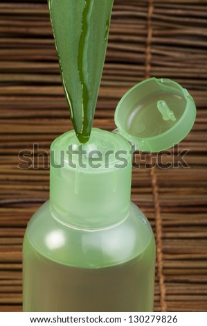 Green cosmetic bottle, green leaf and drop